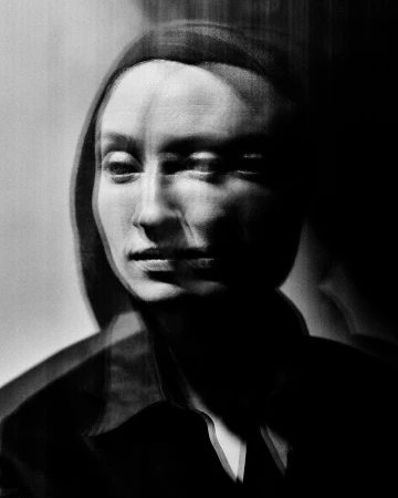 Black and white portrait of a woman with a serious expression, created with long exposure and motion blur effect for artistic effect.