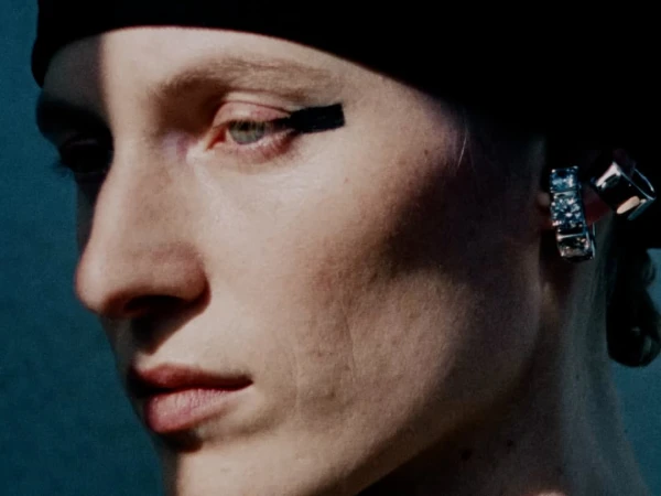 Close-up shot of a model with striking eye makeup and large, blocky earrings, creating a bold and artistic fashion statement.