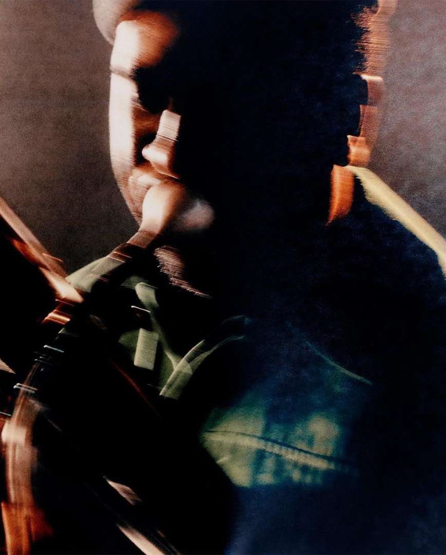 Abstract portrait of a man wearing a hat, captured with a blurred motion effect in a dark, moody, and artistic setting.