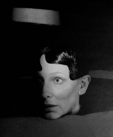 Portrait of a woman with sculpted dark hair and intense expression captured in low-key lighting by Jack Davison