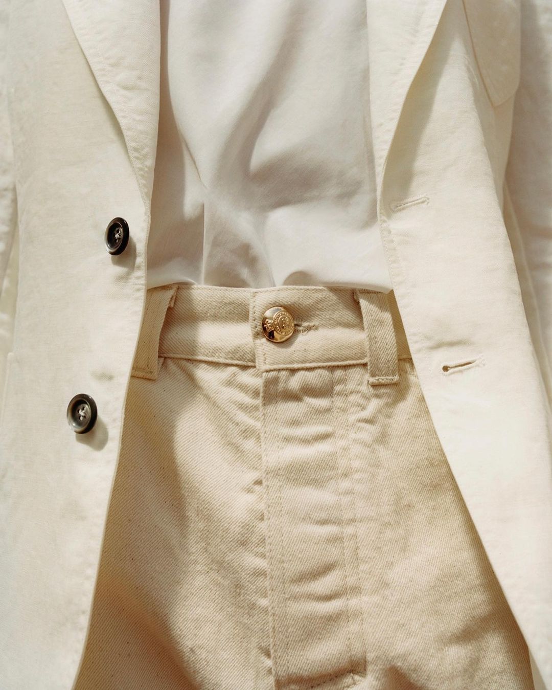 Close-up of a blazer, shirt, and pants combination, showcasing a light-colored, fashionable outfit for a sophisticated or casual look.