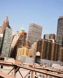 Low-angle view of New York City skyscrapers and rooftops captured from a bridge framework by Jack Johnstone