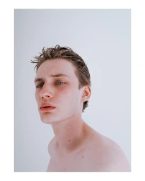 Portrait of a young man with wet hair and a neutral expression against a plain white background