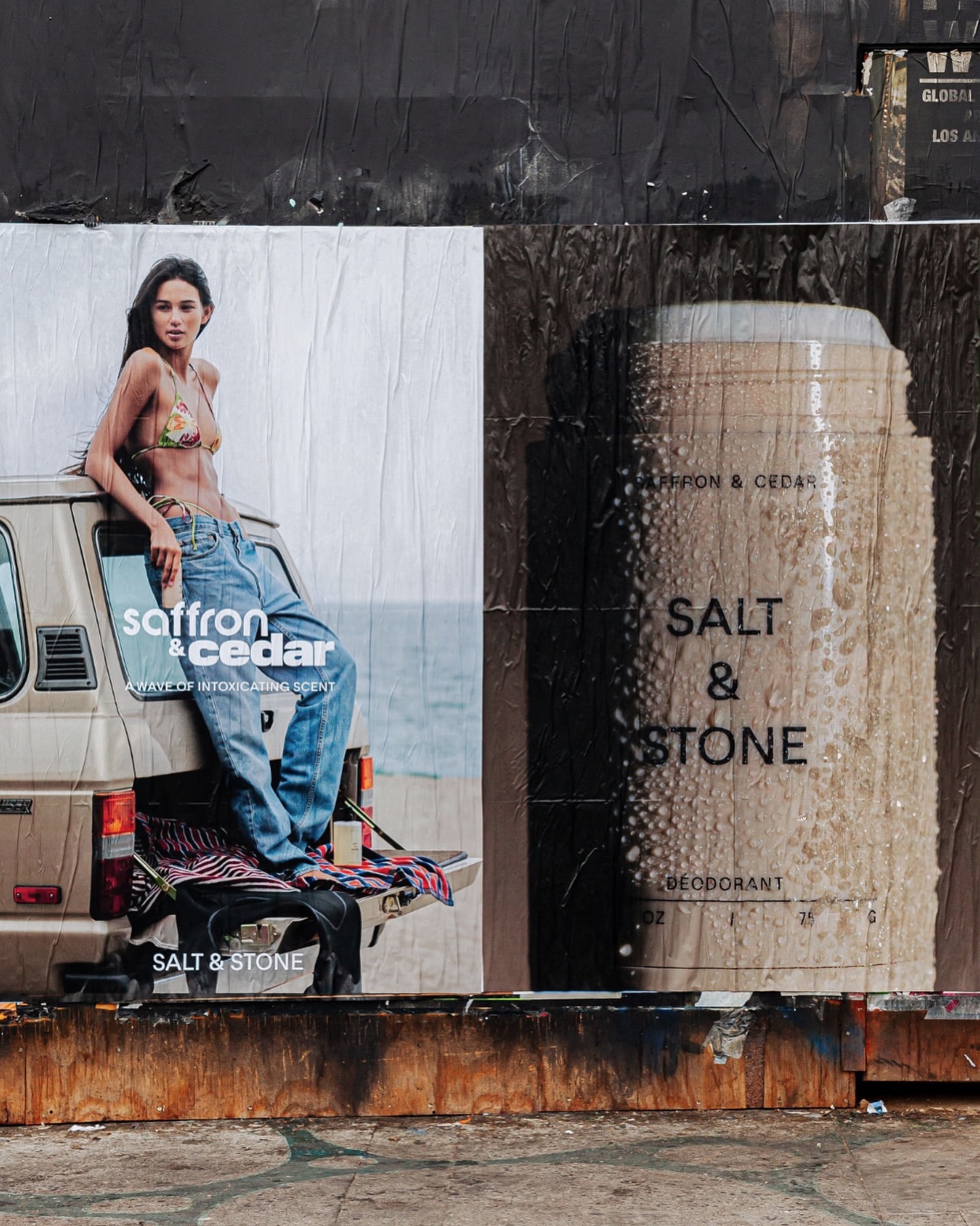 Torn advertisement featuring a model in a bikini and jeans, posed on a car bumper next to a deodorant ad for Salt & Stone.