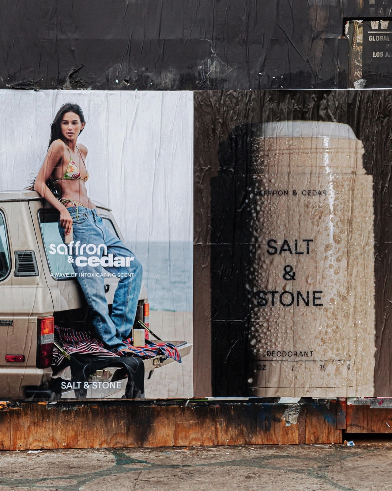 Wheatpaste posters on a weathered wall featuring a woman in a bikini and jeans leaning on a beige SUV and a deodorant product package