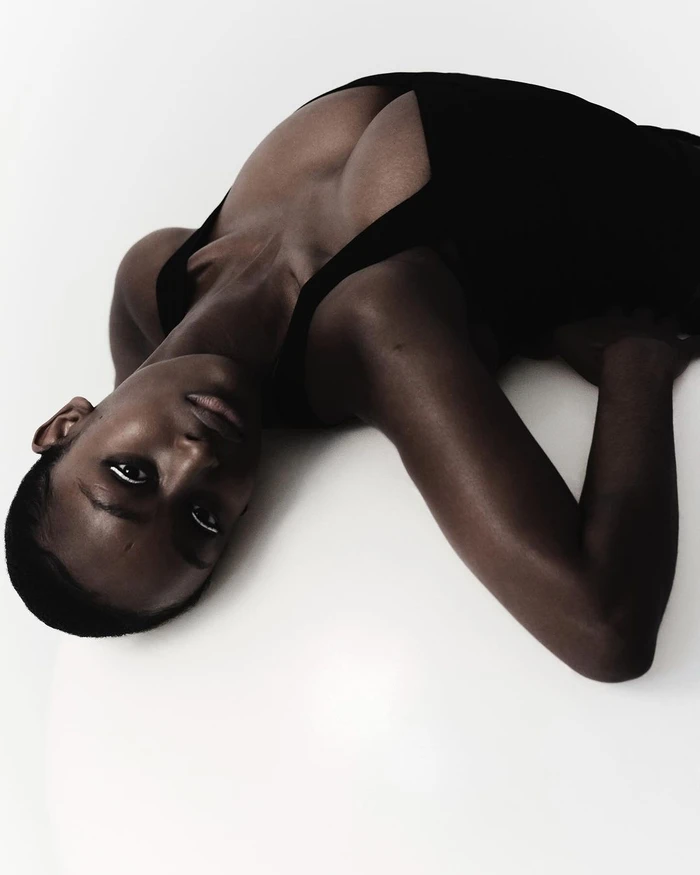 Model wearing a black top reclining on a white seamless background photographed by Jai Odell in London.