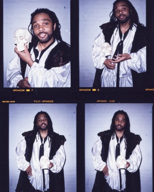 Man in Renaissance-style costume holds a skull in a photo studio. Four images of the man are visible within the frame. Dark hair and beard.
