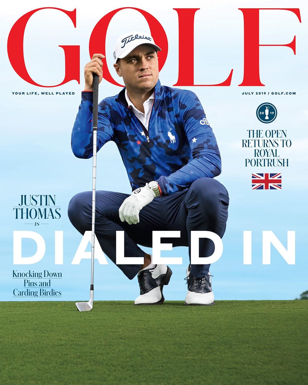 Golf magazine cover featuring Justin Thomas with a golf club, wearing a blue patterned shirt and navy pants on green grass.