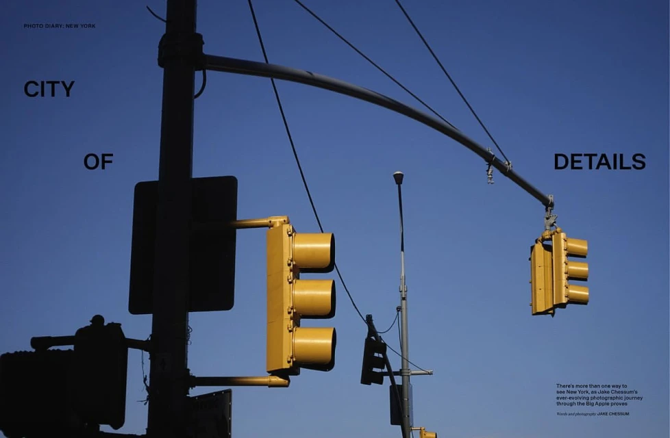 Urban shot of yellow traffic lights against a clear blue sky, capturing a city's details and infrastructure in daylight.