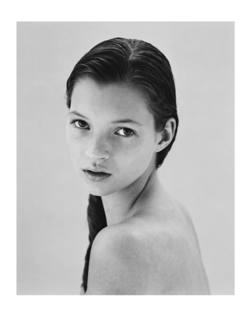 Black-and-white portrait of a young adult woman with dark hair styled in a braid, gazing at the camera against a neutral backdrop.