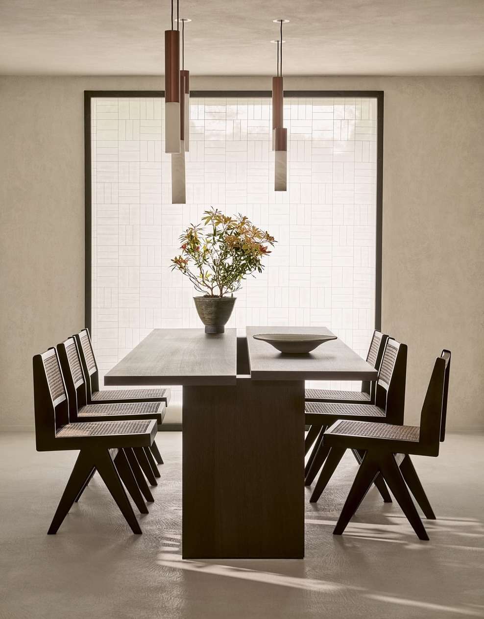 Contemporary dining room featuring a dark wood table set with a ceramic bowl, surrounded by matching chairs and modern pendant lights.