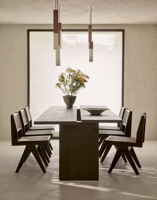 Contemporary dining room featuring a dark wood table set with a ceramic bowl, surrounded by matching chairs and modern pendant lights.