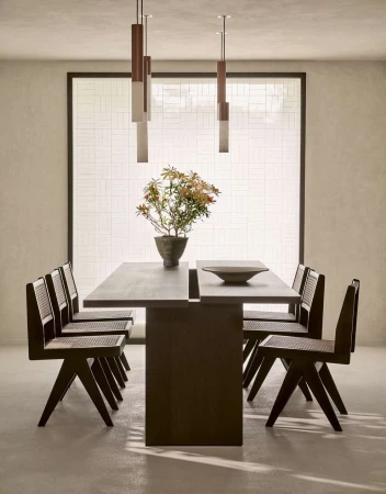 Contemporary dining room featuring a dark wood table set with a ceramic bowl, surrounded by matching chairs and modern pendant lights.