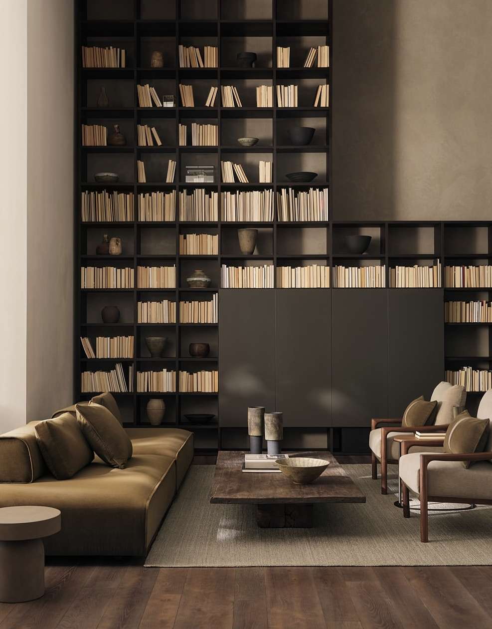 Living room interior with a brown sofa, chairs, a coffee table, and a tall bookshelf filled with books, creating a cozy and inviting space.