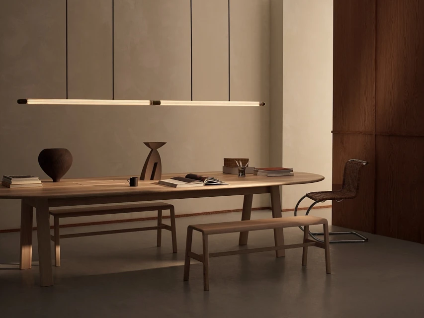 Modern dining room interior featuring a wooden table, chairs, pendant lights, and decorative objects in a minimalist setting.
