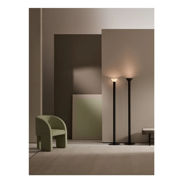 Interior design featuring two floor lamps, a green armchair, and neutral wall panels in a minimalist setting with soft lighting.