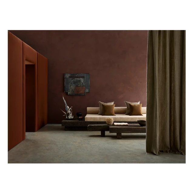 Contemporary interior showcases a neutral sofa with cushions, rustic wood tables, modern art, and a rich earth-toned color palette.