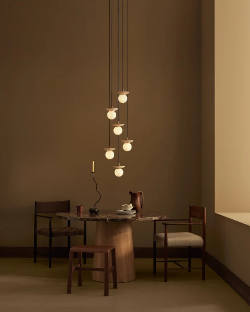 Contemporary interior featuring a dining table set with plates and a pitcher, illuminated by a modern pendant light fixture.
