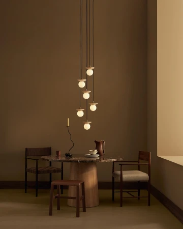 Contemporary interior featuring a dining table set with plates and a pitcher, illuminated by a modern pendant light fixture.