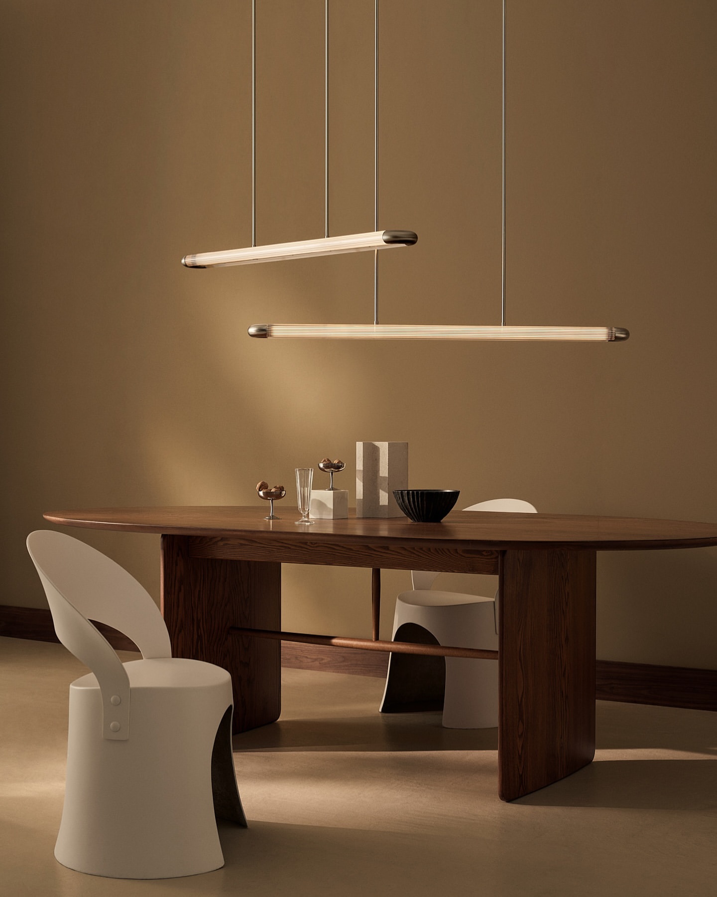 Minimalist interior featuring a wooden dining table with a black bowl and clear glasses, complemented by modern pendant lighting.
