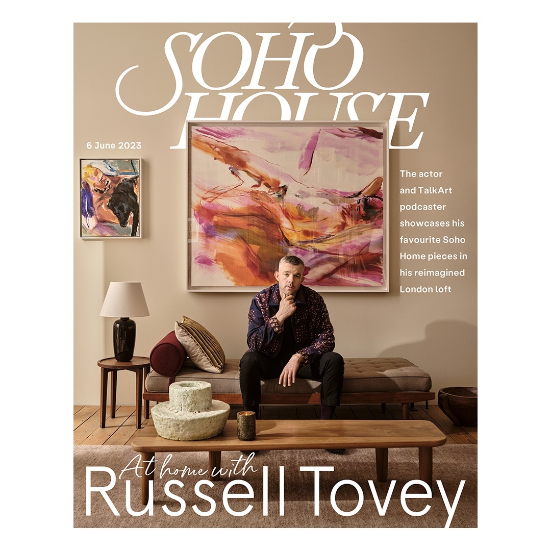 Magazine cover of Soho House featuring Russell Tovey sitting in a living room with modern decor, abstract art, and neutral color scheme.