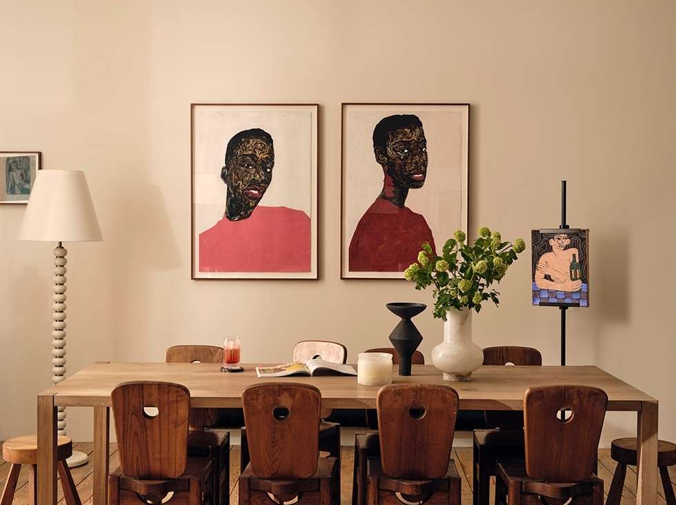 Interior dining room featuring a wooden table with chairs, artwork on the wall, flowers in a vase, and a standing lamp.