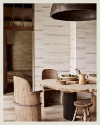 Rustic wooden dining table and chairs with earthenware pitcher in a neutral interior space photographed by Jake Curtis