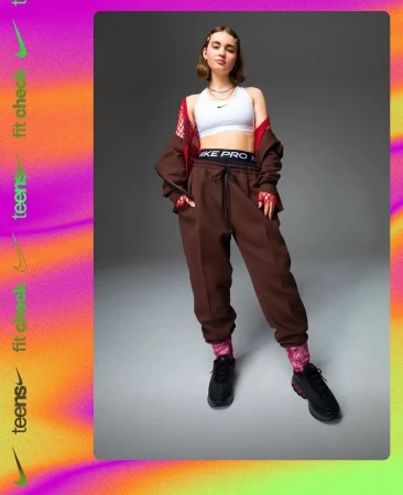 Full-length shot of a woman in a white sports bra, brown sweatpants, and black sneakers against a gradient background. Nike Pro waistband detail.