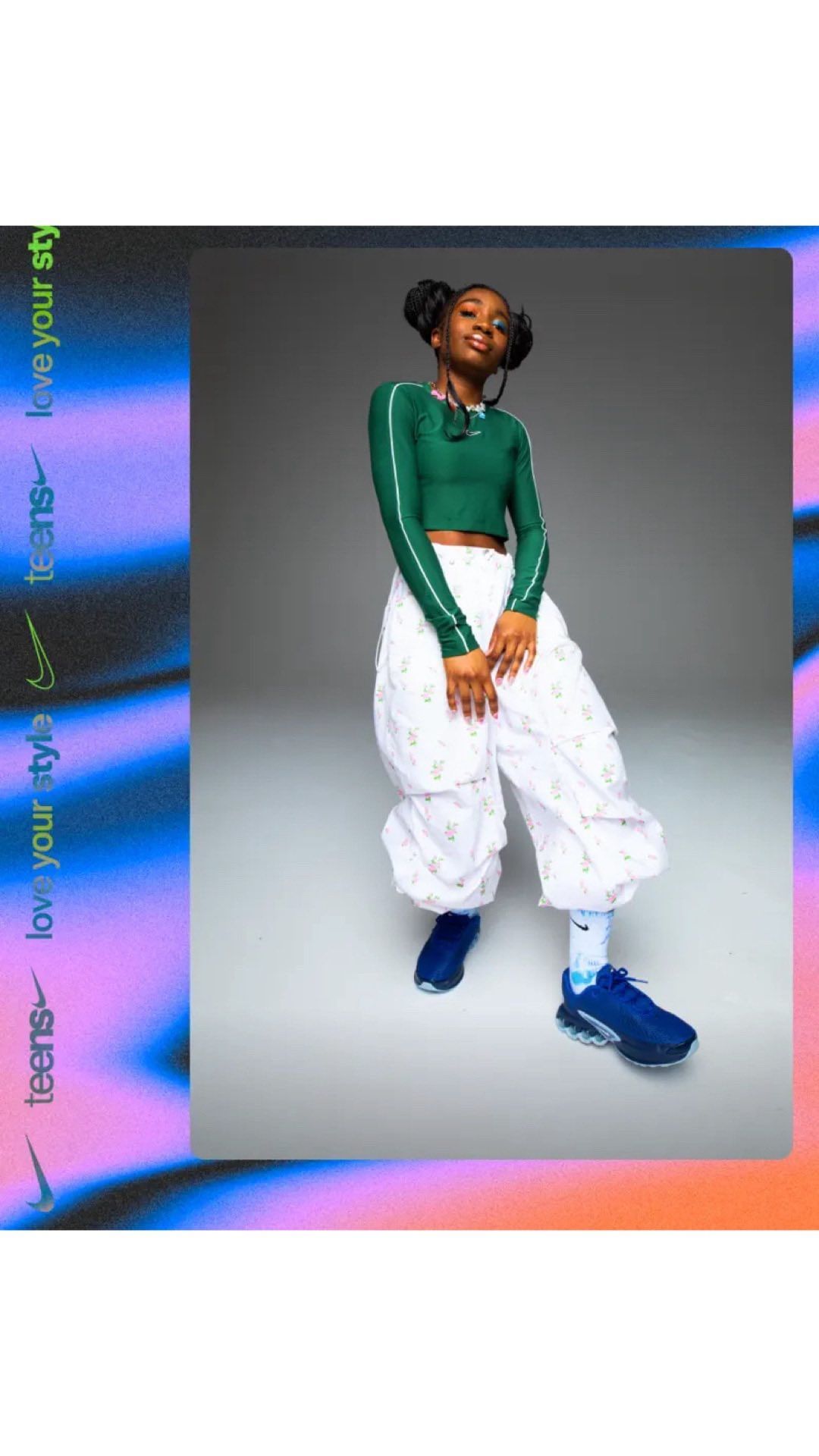 Full shot of a stylish young woman in a green crop top and patterned white pants, posing in a studio with neon accents.