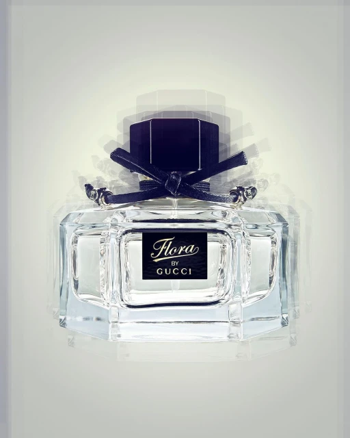 Clear glass perfume bottle with black cap and black bow. The bottle has a black label with the brand name Flora by Gucci.