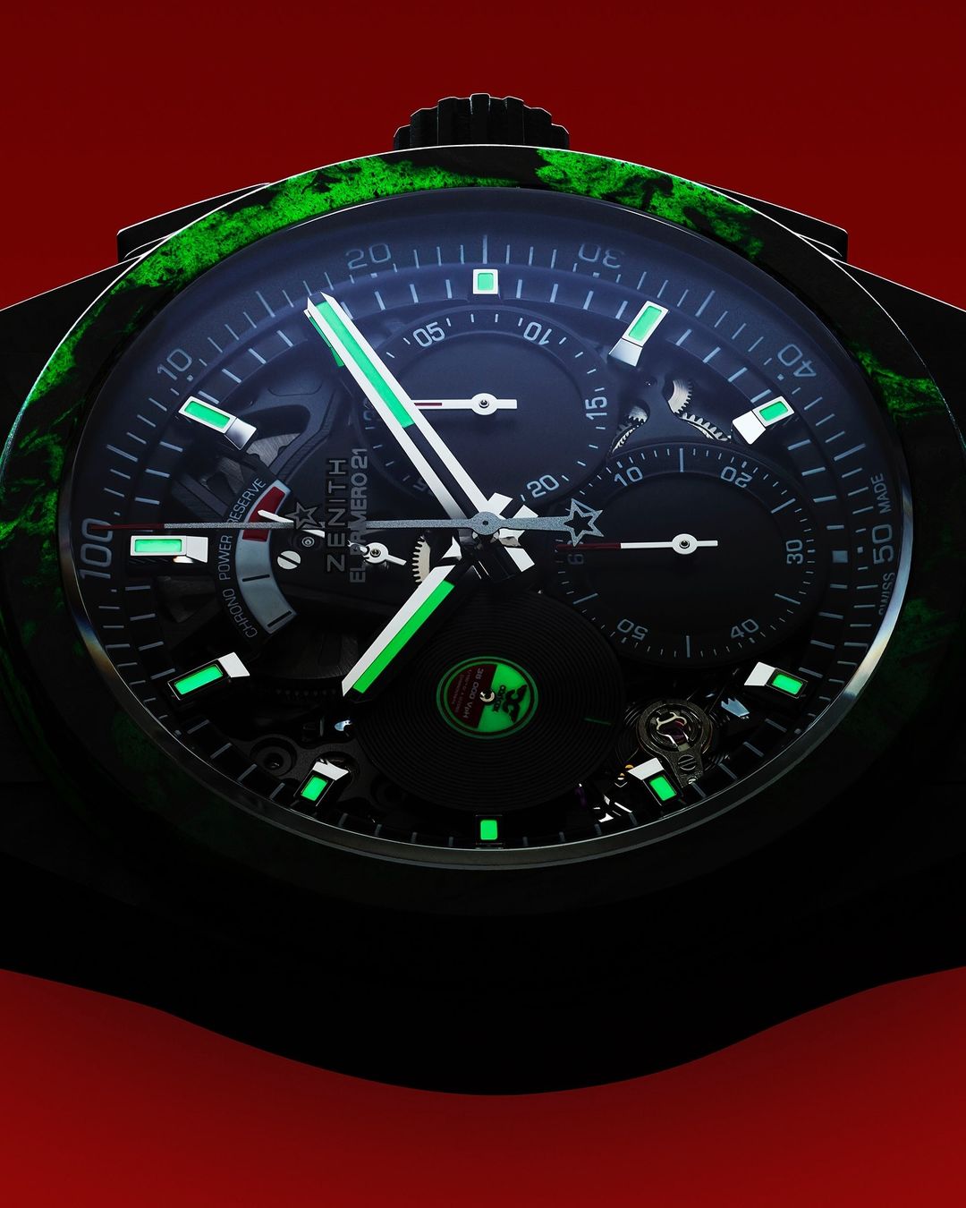 Close-up of a luxury wristwatch with a black dial, green accents, and intricate details, set against a red background.