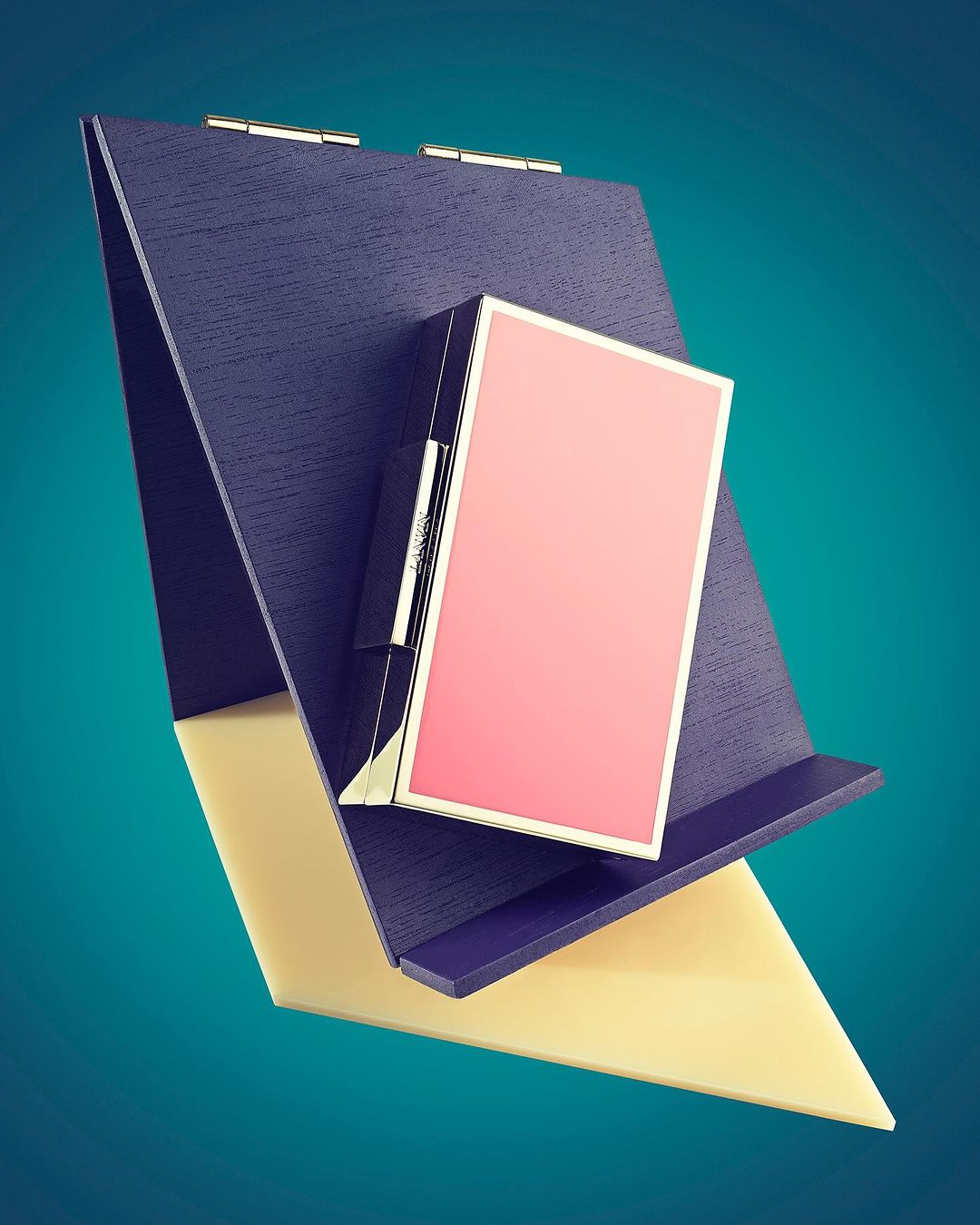 Elevated view of an open book with a pink book resting on the side, showcasing its cover, binding, and the angle created by the support.