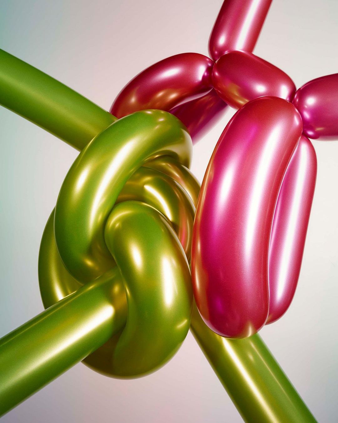 Close-up of green and pink twisted, knotted, and inflated balloon animal figure, lit dramatically against a soft gradient background.