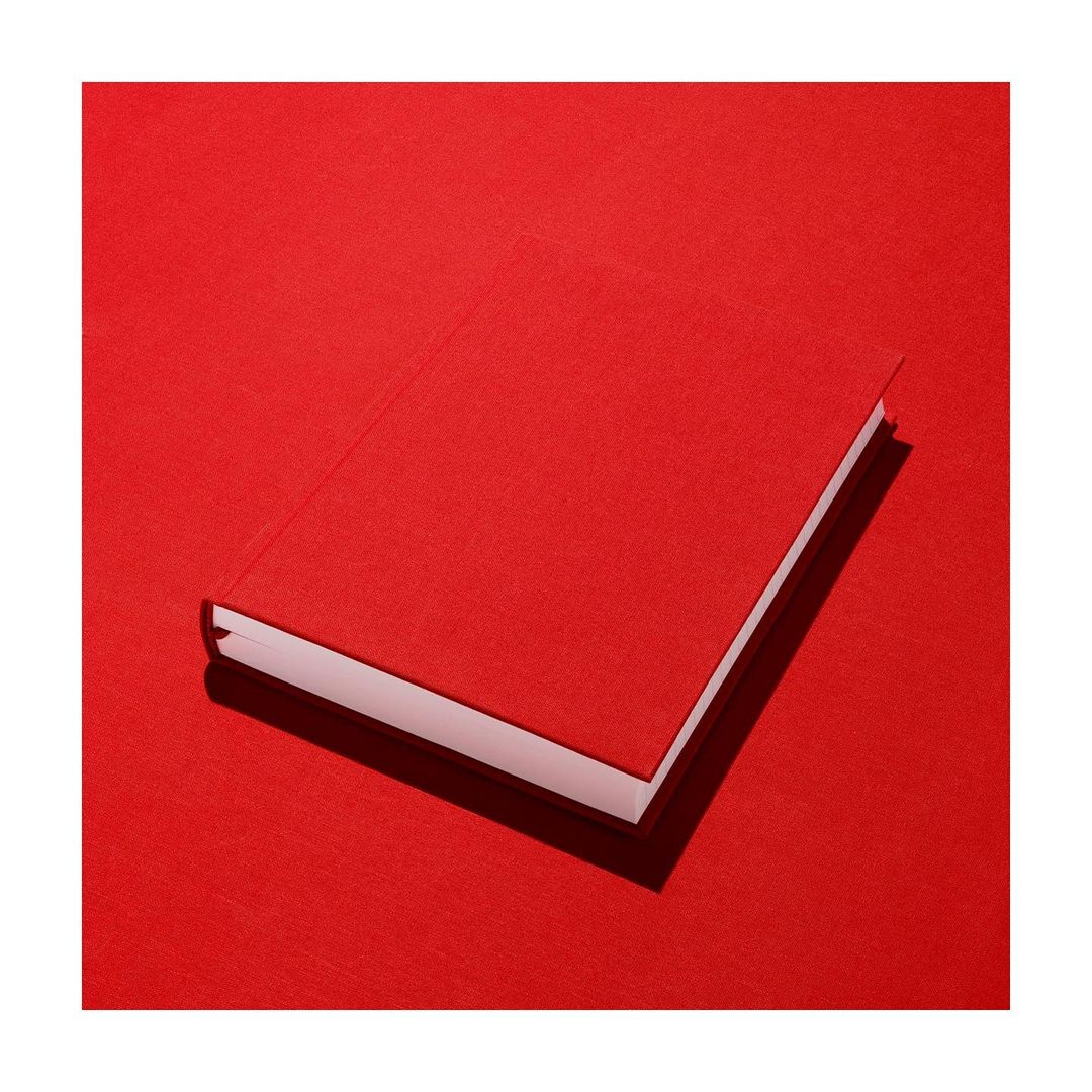 Overhead shot of a closed, red book lying on a matching red surface with slight shadow, simple and minimalistic.
