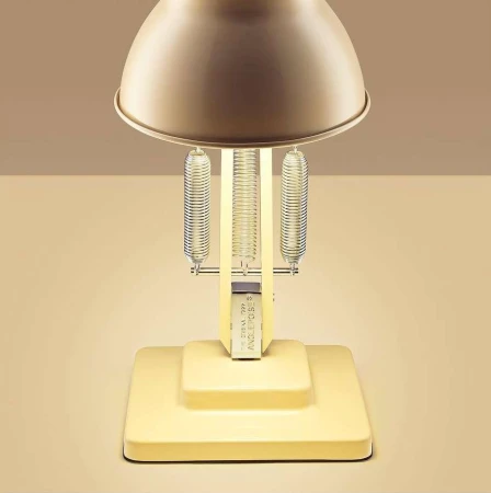 Close-up studio shot of a yellow Anglepoise lamp with springs, showcasing its design and functionality against a neutral background.