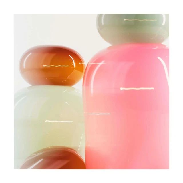Abstract glass art pieces stacked on top of each other in pink, orange, green, and beige tones in a brightly lit photo studio.