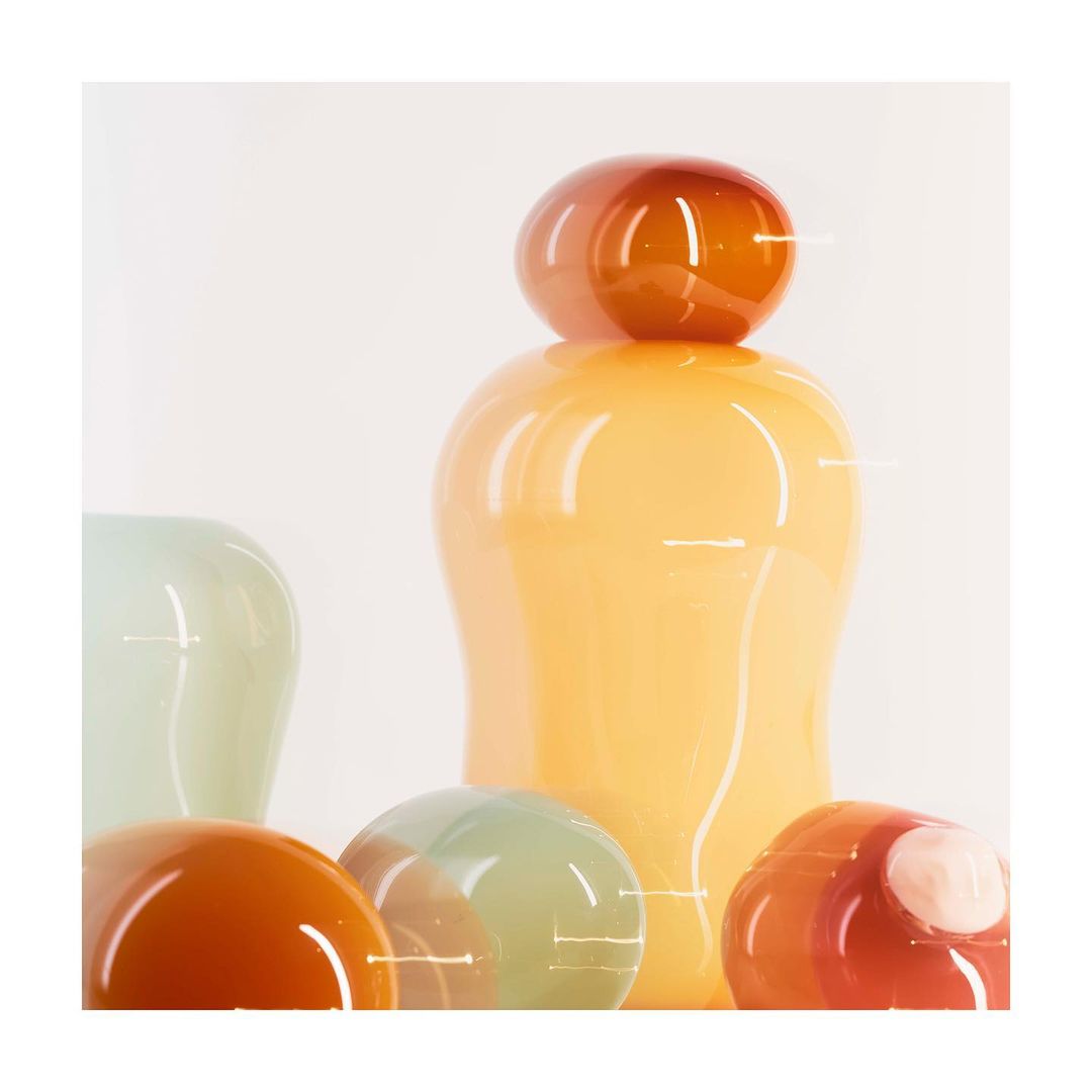 Still life shot of an arrangement of glossy, translucent orange, amber, and pale green glass vases and spheres on a white background.