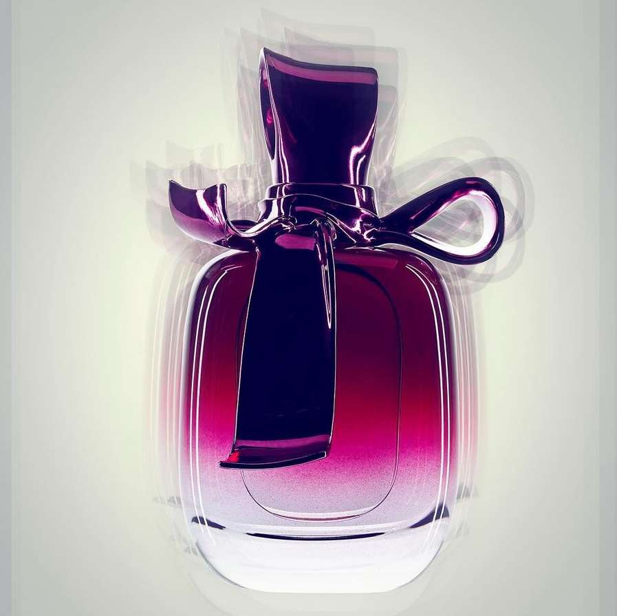 Elegant perfume bottle with a distinctive ribbon design and a smooth gradient of dark purple to clear glass, illuminated by soft studio lighting.