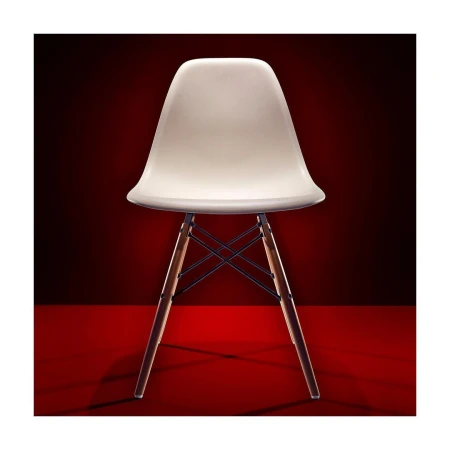 A studio shot of a modern white plastic chair with wooden legs against a graduated red background.