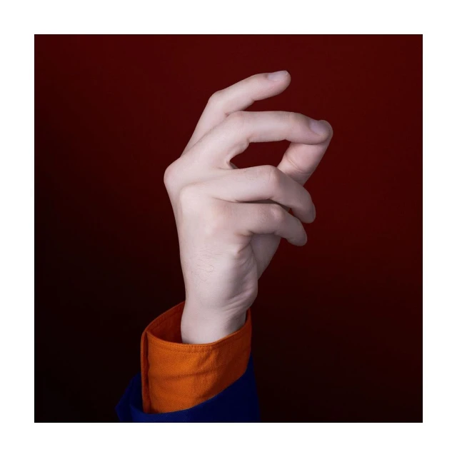 Close-up studio shot of an adult hand with fair skin, showing fingers slightly curled. Hand is framed against a gradient red background.