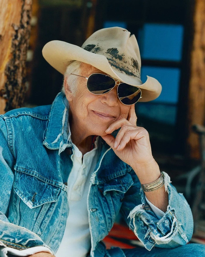 Ralph Lauren wearing aviator sunglasses, a cowboy hat, and a distressed denim jacket by James Harvey-Kelly.
