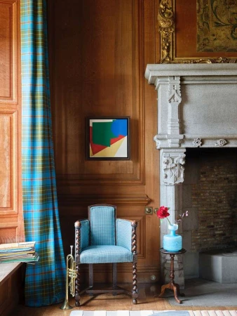 Living room interior featuring a blue patterned chair, decorative fireplace, trumpet, and modern art, creating a stylish and artistic home setting.