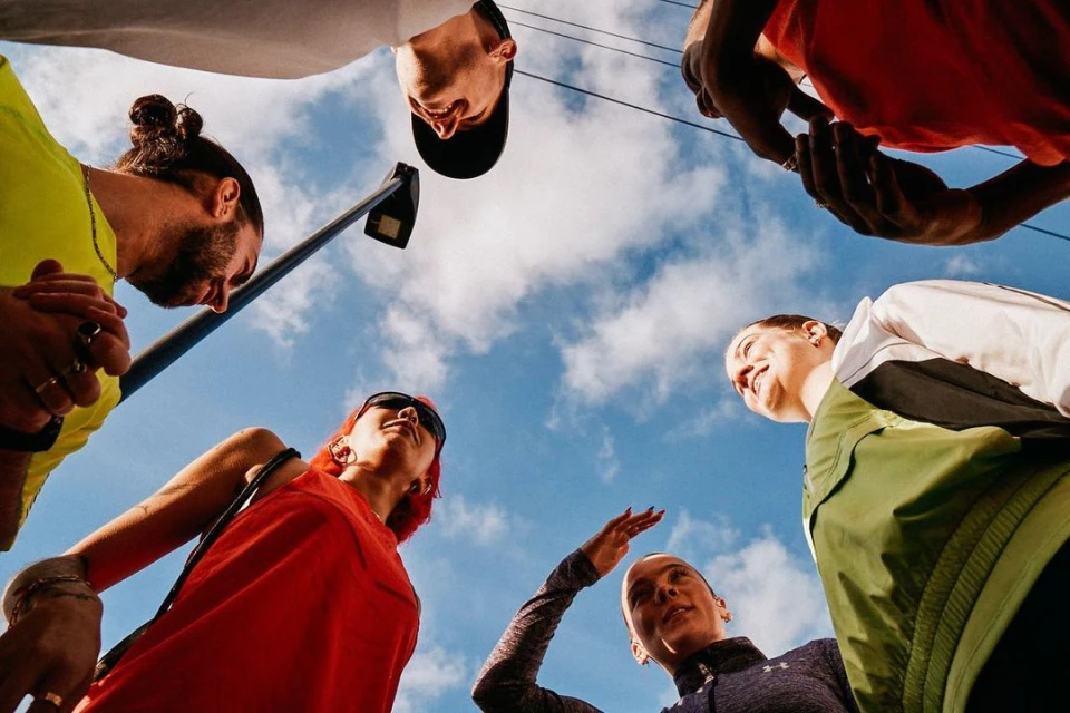 Low-angle shot of six diverse adults in casualwear against a cloudy sky, creating a cheerful, collaborative, and inclusive vibe.