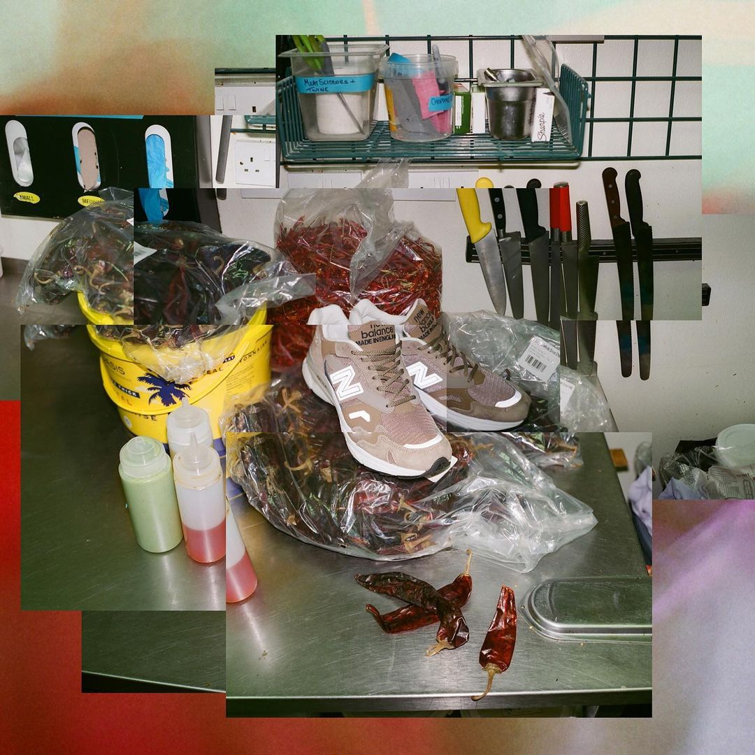 Still life featuring athletic shoes, red chilis, bottles, and kitchenware arranged on a stainless steel countertop in a kitchen setting.