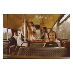 Group of young girls in school uniforms on a bus interior captured by James Perolls in London.