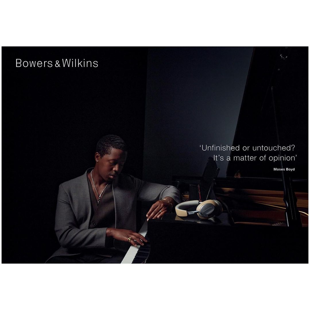 African-American man playing piano with headphones in studio, in dark, with Bowers & Wilkins logo and a quote about opinion.