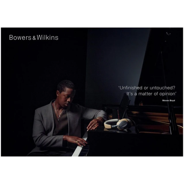 African-American man playing piano with headphones in studio, in dark, with Bowers & Wilkins logo and a quote about opinion.