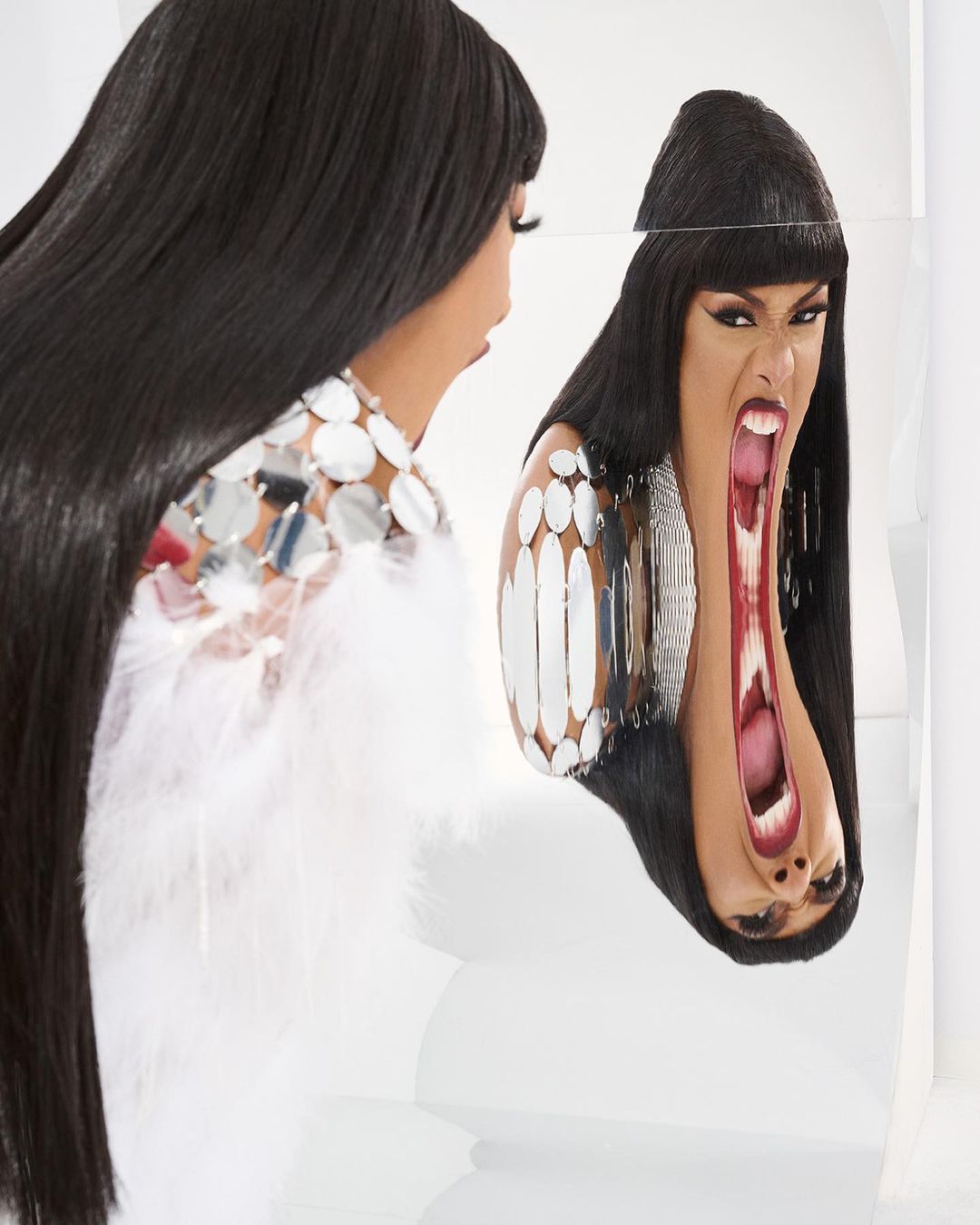 Woman with long dark hair gazes into a distorted mirror, creating a surreal and dramatic reflection in a light-filled photo studio.
