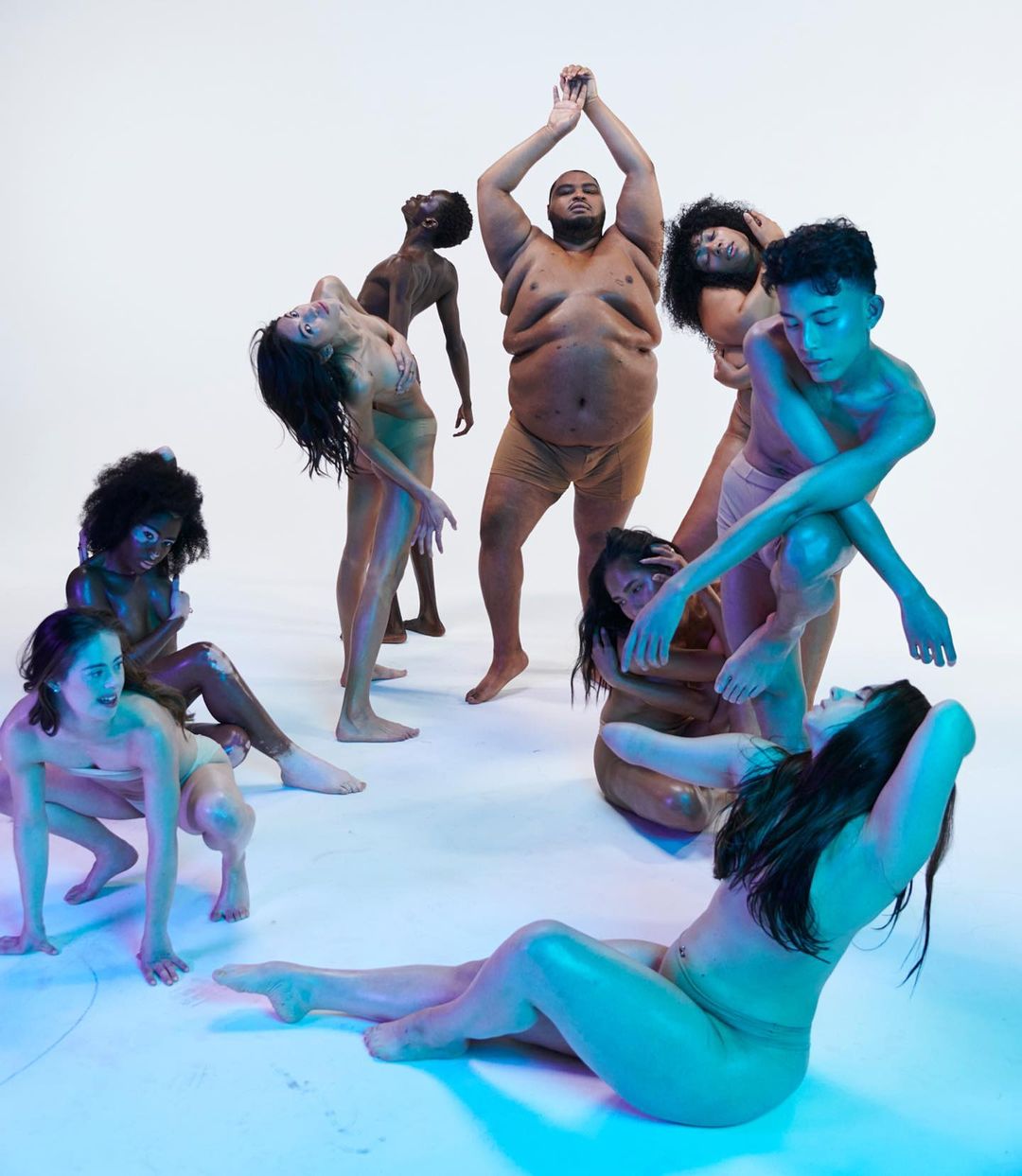 Diverse group of nine nude people arranged in a circle in a photo studio, creating an artistic and inclusive visual statement.
