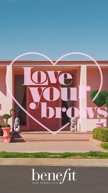 Exterior shot of a pink single-story house with a brown lawn and driveway, framed by a pale pink heart-shaped graphic overlay.